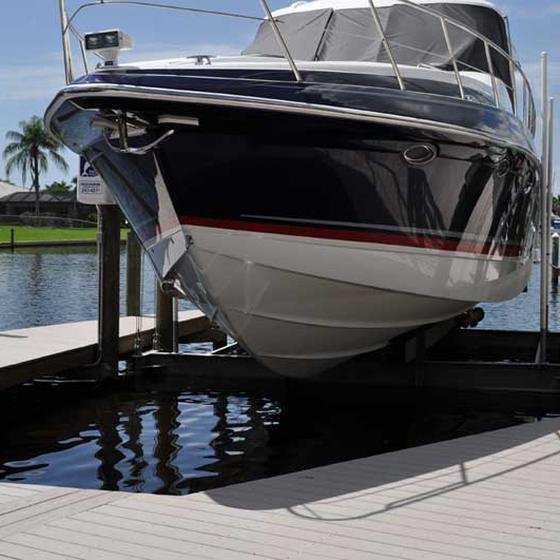 Cruiser raised on a boat lift beside a dock