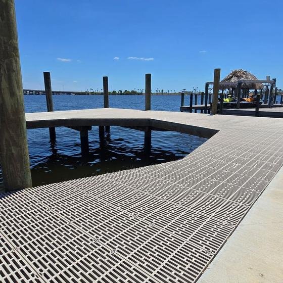 Curved dock walkway with grated decking leading to a tiki hut