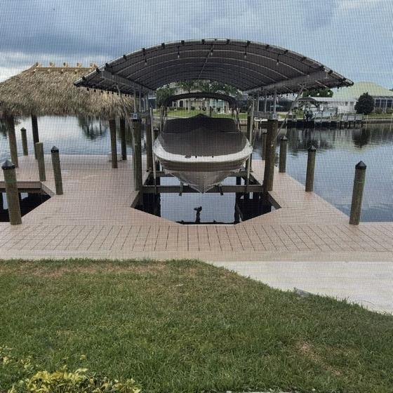 Boat on a lift under a dark canopy beside the tiki hut