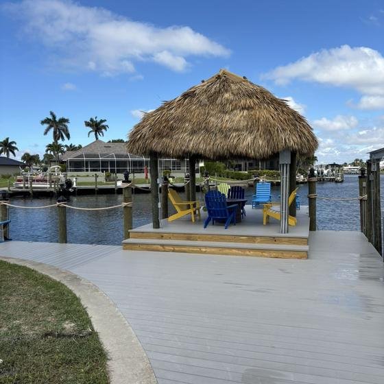 Square tiki hut on a raised Slate Gray vinyl deck with colorful Adirondack chairs